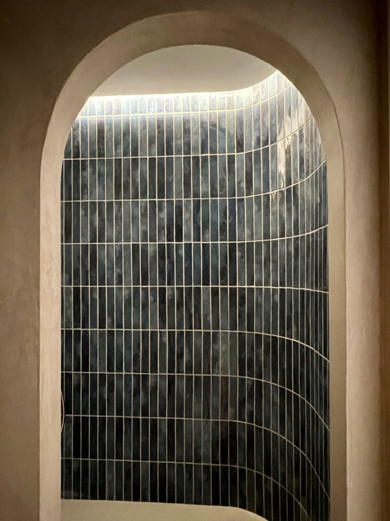 Curved shower lined with green glazed tiles