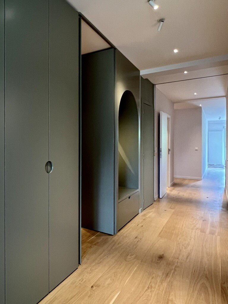Entrance hall with sage green built-in cupboards and arched niche