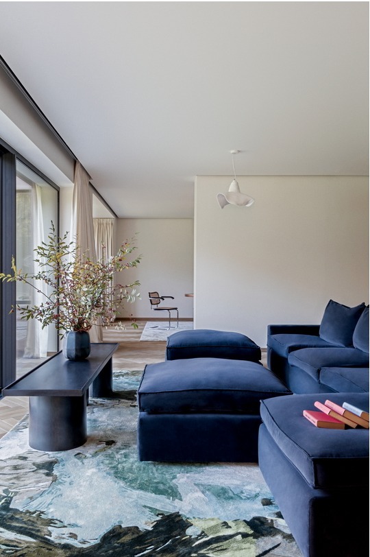 Steel coffee table in a living room with a blue sofa and herringbone parquet