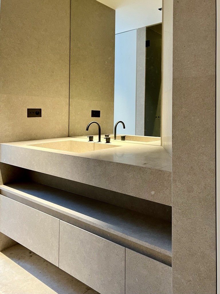 Beige stone washbasin unit with open shelf and mirror