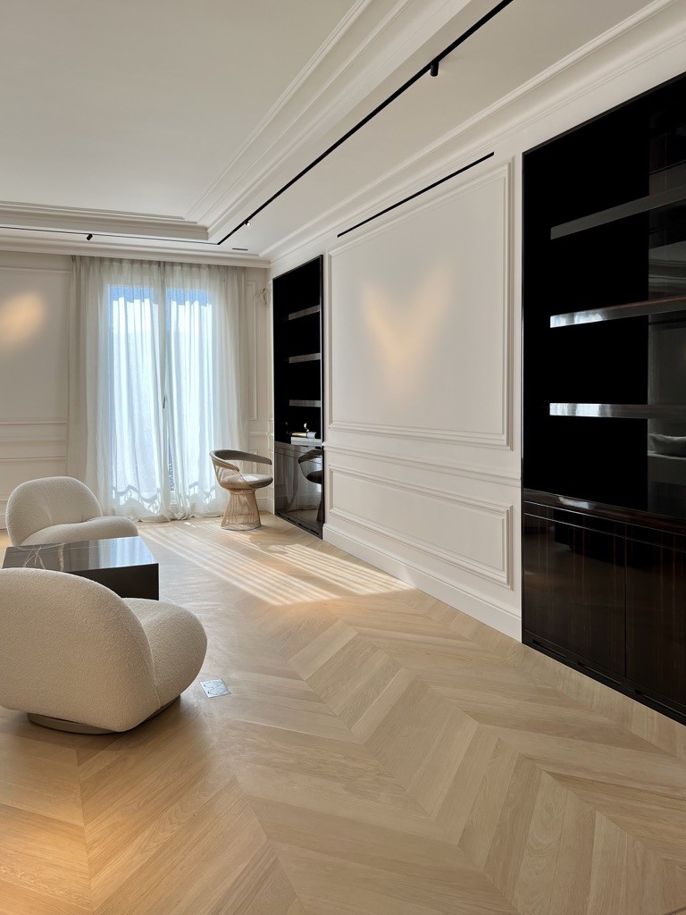 Living room with mouldings, black lacquered bookcases and chevron oak parquet